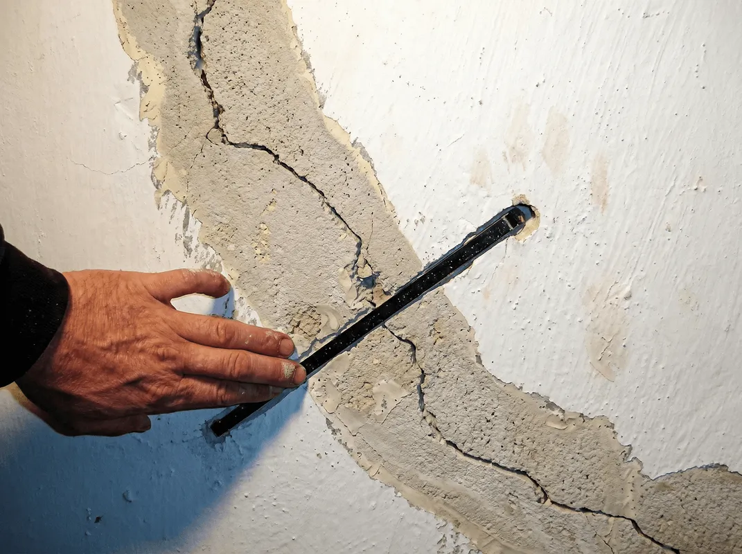 A wall with a large crack is being inspected by a professional in ,