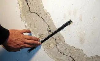 A wall with a large crack is being inspected by a professional in ,